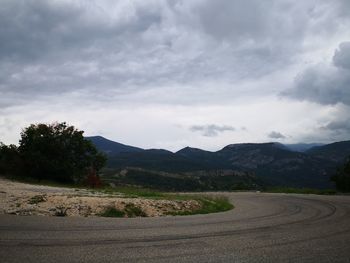 Scenic view of road by mountains against sky