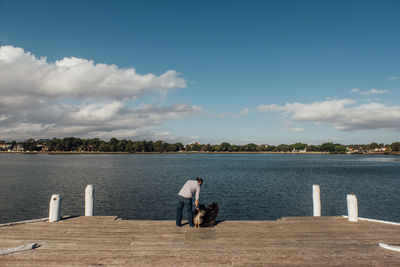 Rear view of men fishing in lake against sky