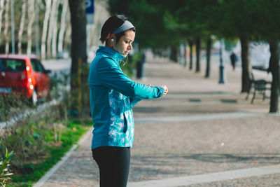 Side view of woman checking time while standing on promenade