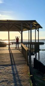 Woman standing on pier by sea against sky