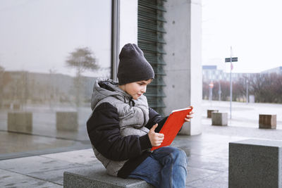 Boy using digital tablet on seat