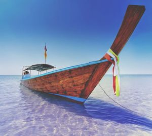 Boat moored on sea against clear blue sky