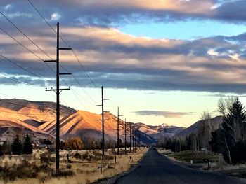 Road by landscape against sky during sunset