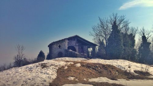 House amidst trees and buildings against sky