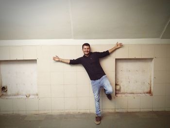 Portrait of young woman jumping against wall