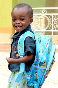 Portrait of smiling boy standing against wall