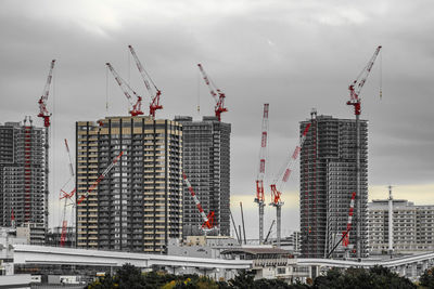 Cranes in city against sky