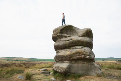 Man standing on rock against sky