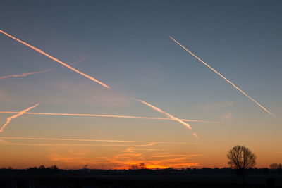 Scenic view of vapor trails in sky at sunset