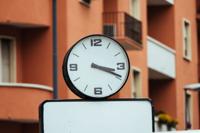Clock against building in city
