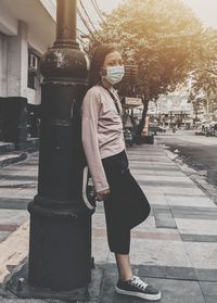 Full length of woman standing on footpath in city