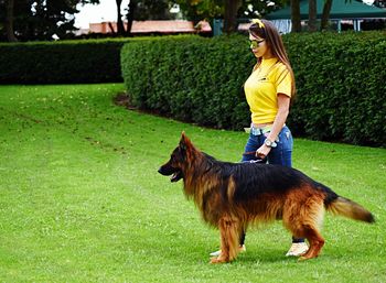 Young woman with dog walking on grassy field at park