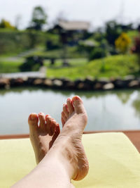 Low section of person relaxing by swimming pool