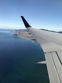 Airplane flying over sea against blue sky