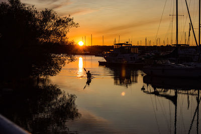 Silhouette sailboats moored on lake against sky during sunset