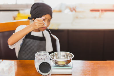 Young boy measuring ingredient for baking in kitchen