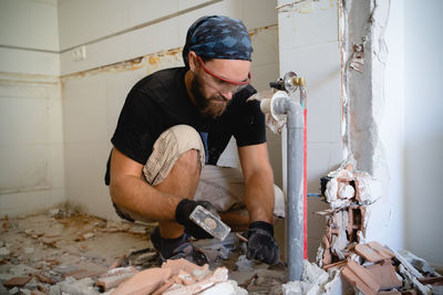 Man working on the home improvement surrounded by debris from a wall