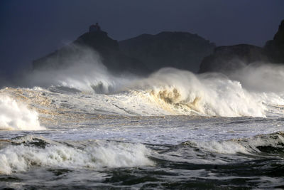 Waves splashing in sea against clear sky