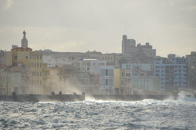 Sea by buildings against sky in city