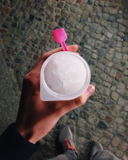 Cropped hand holding white ice cream cup on street