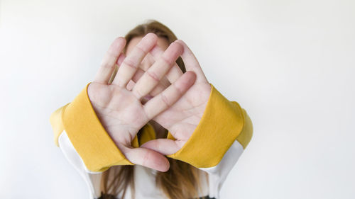 Close-up of woman covering face against white background