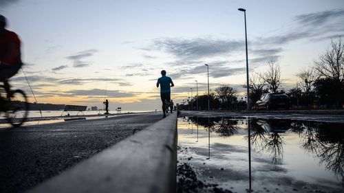 Silhouette man by road against sky