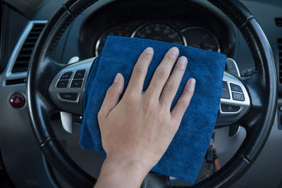 Cropped hand cleaning steering wheel of car with napkin