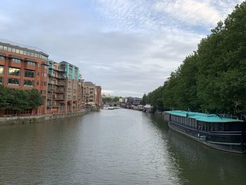 Canal amidst trees against sky in city