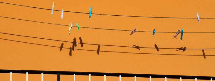 Low angle view of birds perching on cable against orange sky