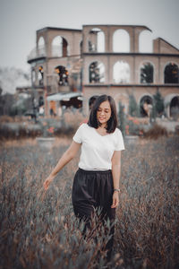 Portrait of young woman standing against plants