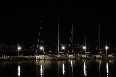 Sailboats moored in harbor at night