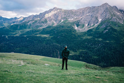 Rear view of man standing on mountain against sky