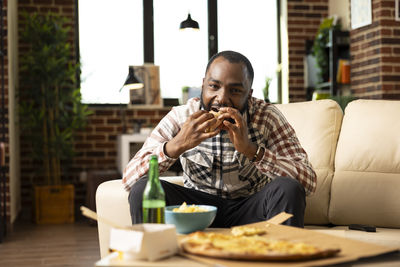 Portrait of young woman eating food at home