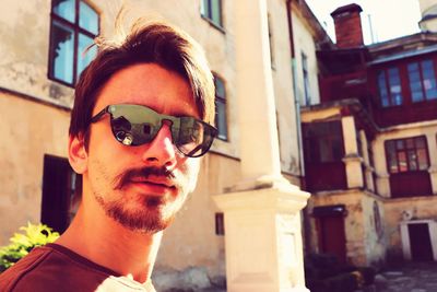 Portrait of young man wearing sunglasses against building