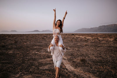 Full length portrait of a young woman standing on desert