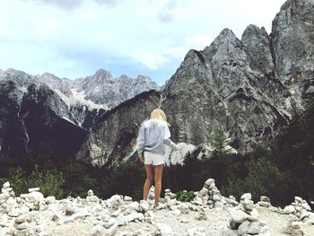 Rear view of woman standing on rocks against mountain