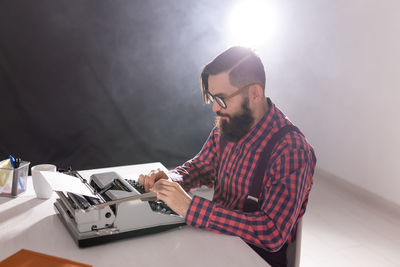 Young man using mobile phone while sitting on table