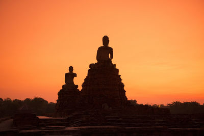 Low angle view of buddha statues against sky during sunset