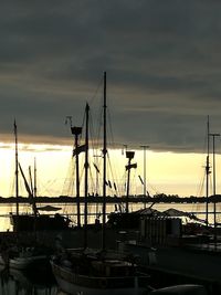 Sailboats moored at harbor against sky during sunset