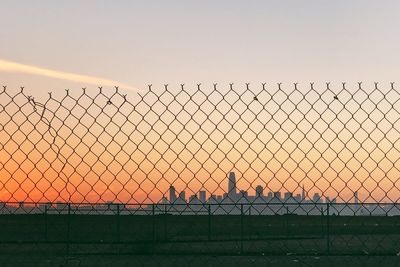 Chainlink fence against sky during sunset