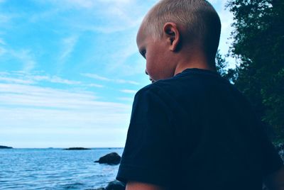 Rear view of man looking at sea against sky