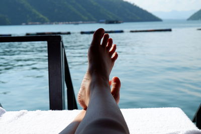 Low section of person relaxing by sea