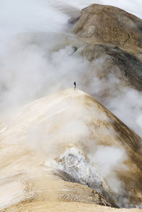 Person standing on mountain in foggy weather 