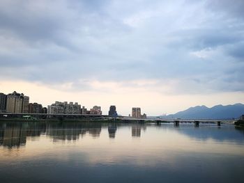 City at waterfront against cloudy sky