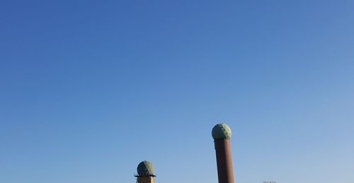 Low angle view of smoke stack against clear blue sky