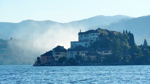 Buildings by sea against sky