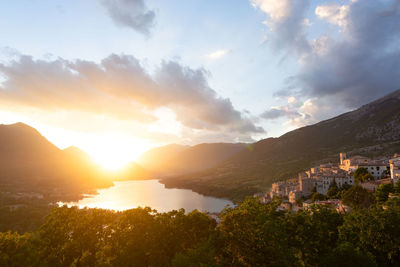 Scenic view of townscape by mountains against sky during sunset