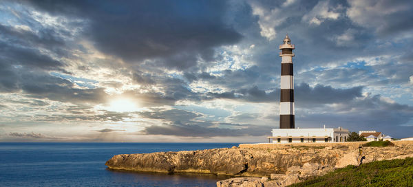 Lighthouse amidst sea and buildings against sky