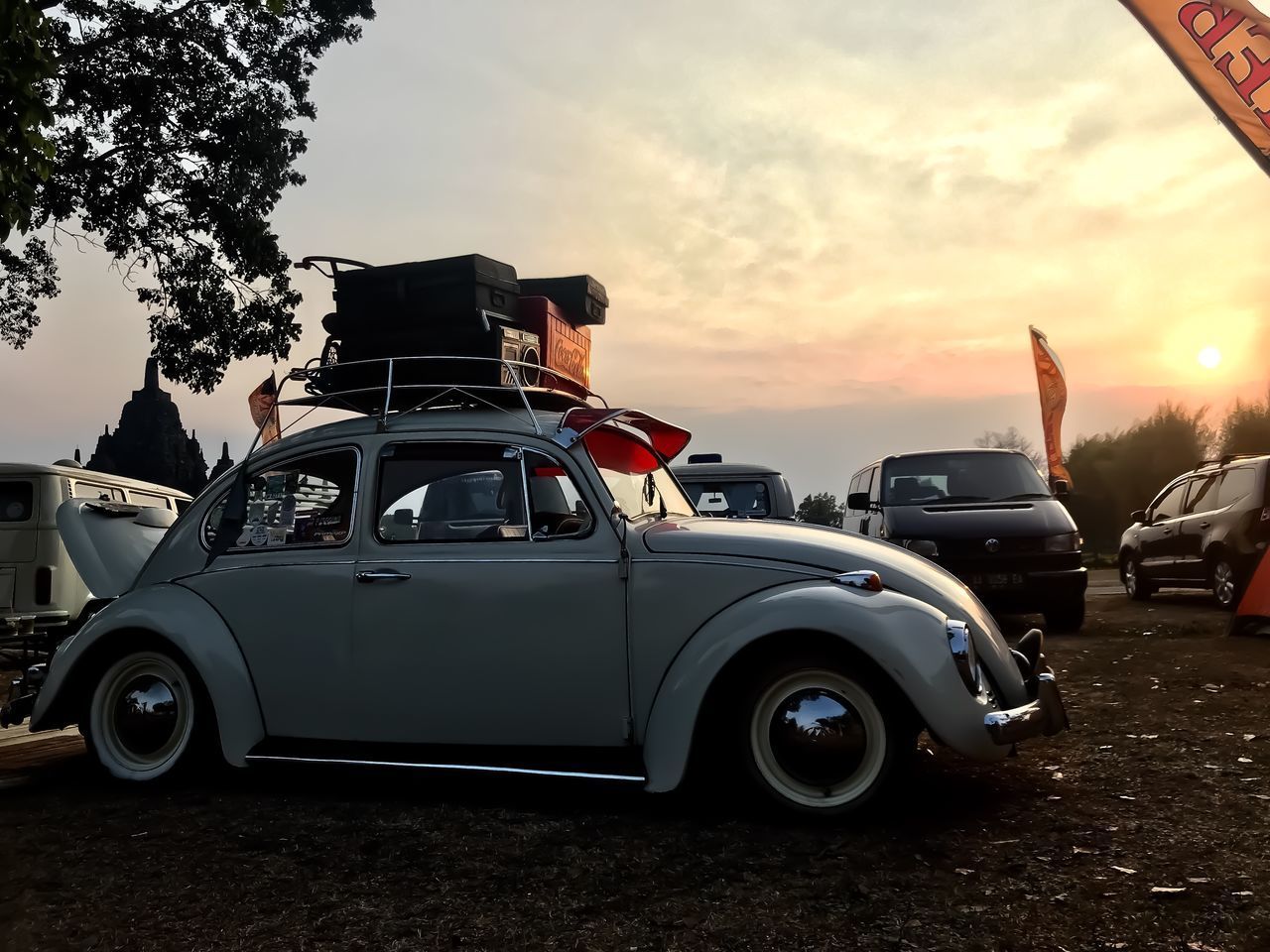 VINTAGE CAR ON ROAD AGAINST SUNSET SKY