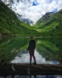 Rear view of woman standing at lake against sky